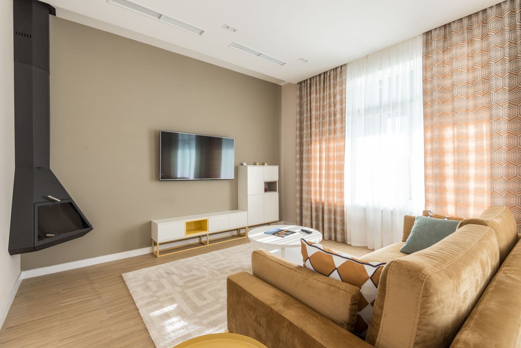 TV mounted on a taupe wall with no visible wires and a white media console below