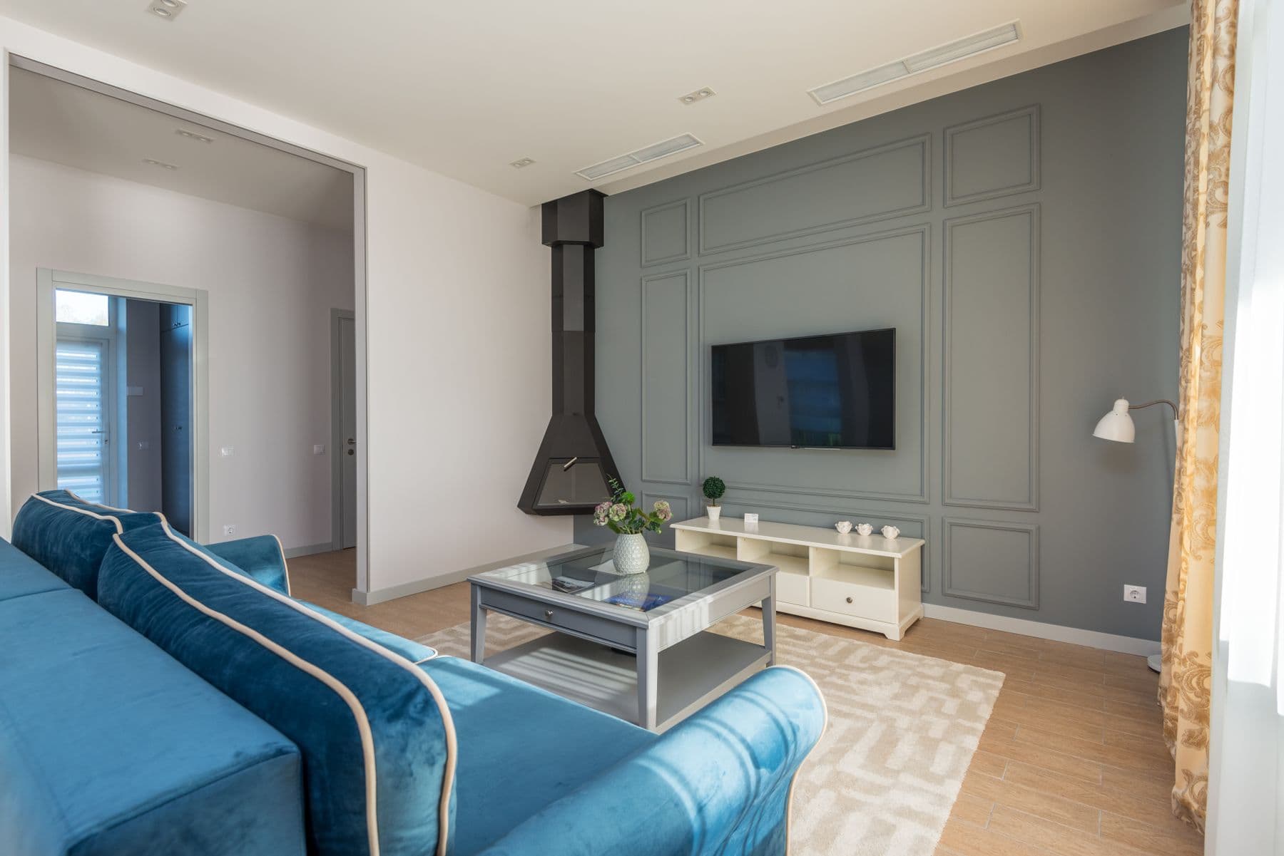 TV wall-mounted flush on a gray paneled feature wall beside a suspended black fireplace