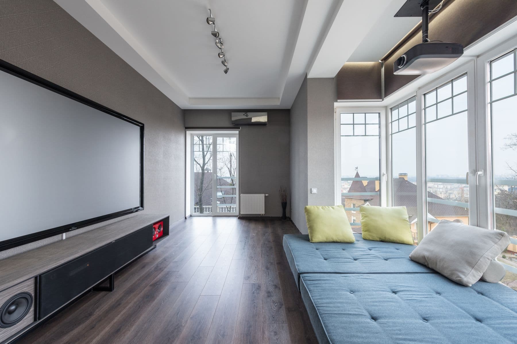 Home theater room with a large projection screen, a media console with built-in speakers, and blue daybed seating